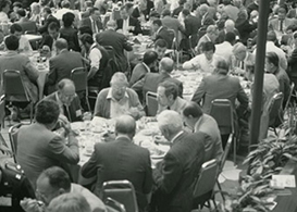 Large group of people eating around multiple round dinner tables