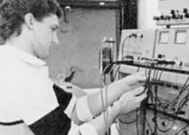Student working on large computer system plugging wires in.