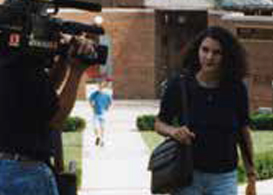 Female student walking on campus. News station videotaping her