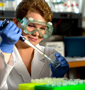 Student extracting a fluid from a glass beaker in a biology laboratory.