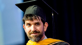 Image shows a professor smiling and wearing academic gowns during Rose-Hulman’s graduation ceremony.