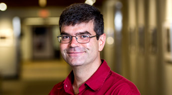 A smiling Dr. Allen Holder standing in a hallway at Rose-Hulman