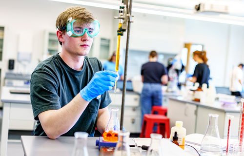 A male student works on an experiment in a chemistry lab.