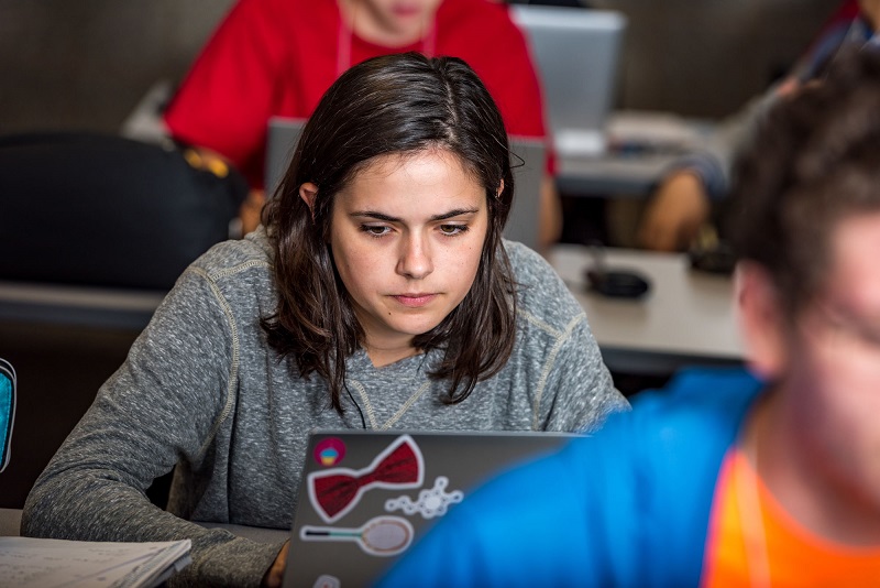 A female high school student looking at her laptop computer.