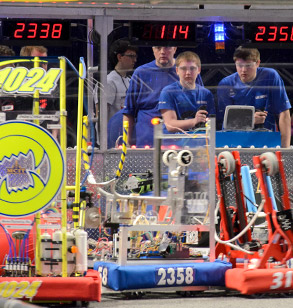 Students in the background remotely control robots in the foreground.