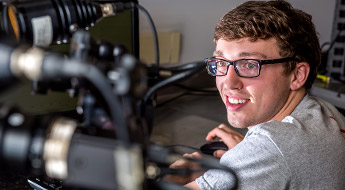 A male student smiling and working on an experiment inside the Orthopaedic Biomedical Engineering Lab