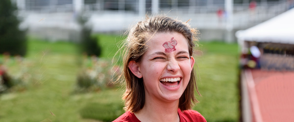 Girl's face with big smile. She has elephant tattoo on her forehead.