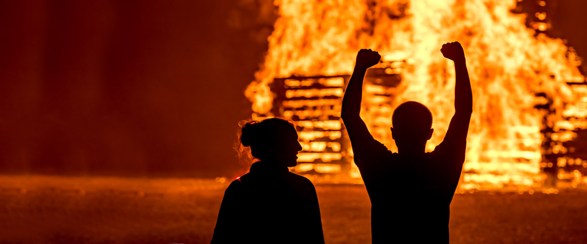 homecoming bonfire with students silhouetted in the light of the flame