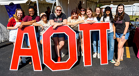 Members of the Panhellenic Council in front of sign