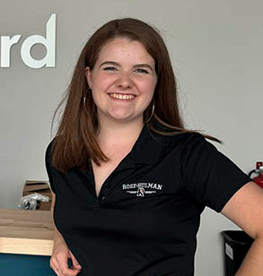 Catherine Hodge stands near a desk and smiles.