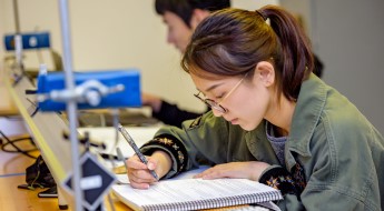 Female student writing in a notebook.