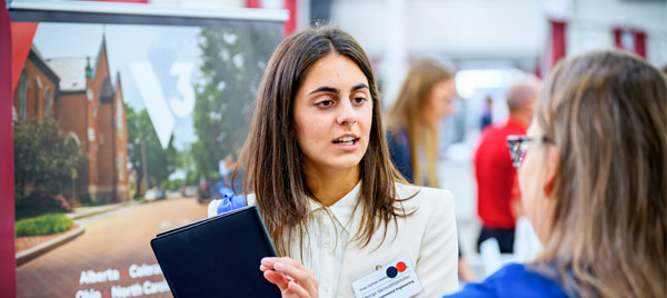Student holds portfolio while talking to employer at Career Fair.