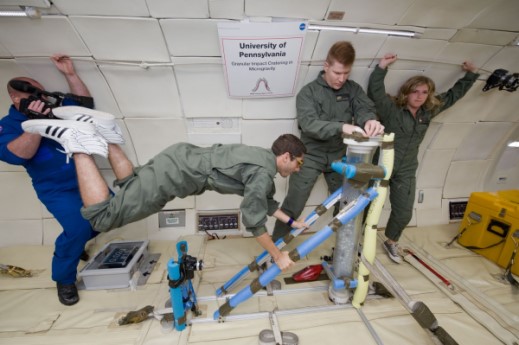 Astronauts in training floating in zero gravity chamber.