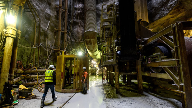 View of workers and machinery operating in a large underground tunnel.