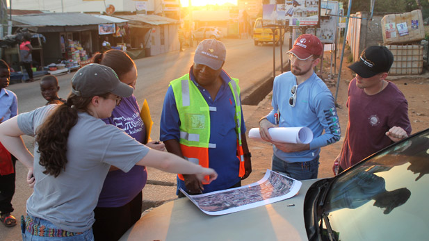 Civil engineering students reviewing plans on street in Ghana.