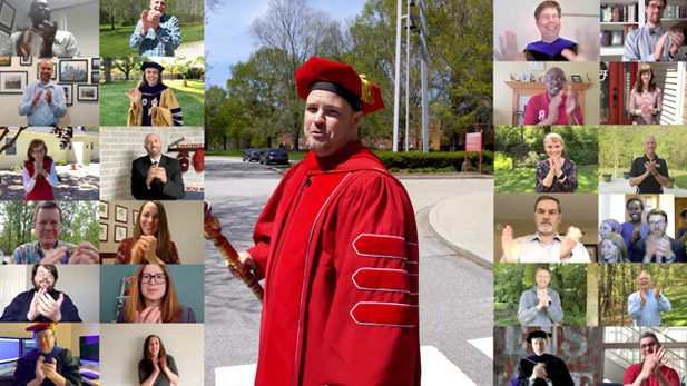 Erik Hayes in center of screen in his graduation regalia. On either side are video chat screens showing about 20 faculty and staff members applauding the graduates.