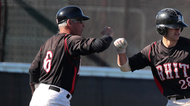 Coach Jeff Jenkins fist-bumping a baseball player.