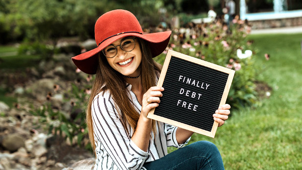 Madison Murphy smiling and holding a sign reading "Finally Debt Free."