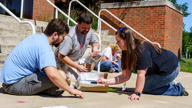 Teachers participating in a STEM activity on the sidewalk.