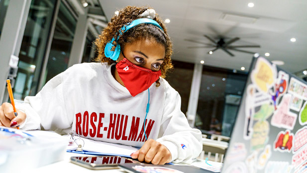 Student wearing headphones working at her laptop computer in the Pi-vilion.