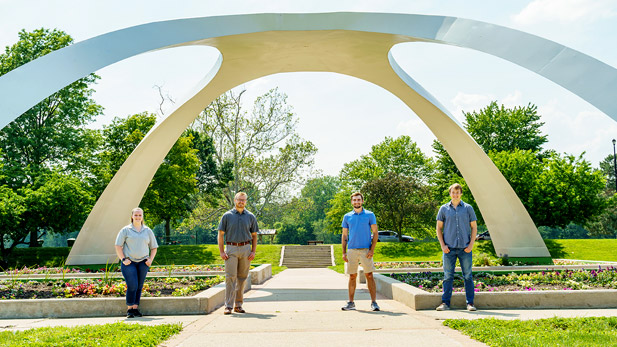 Students posing under arch sculpture at Fairbanks Park.