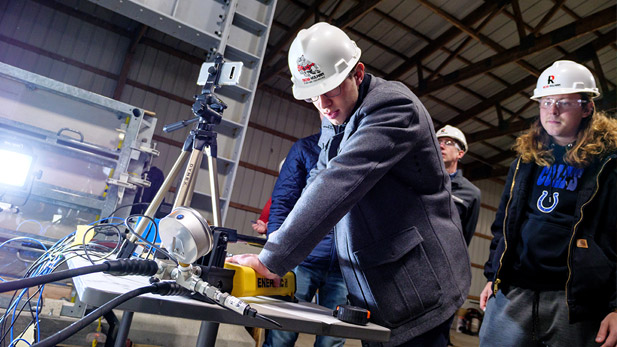 Civil engineering students working in the modular strong-wall structural testing lab wearing hard hats.