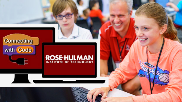 Smiling David Fisher observing a young person working at a computer.