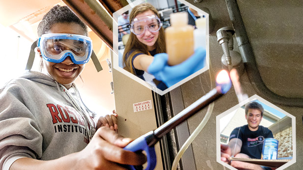 Three students wearing safety goggles and smiling while working on projects.