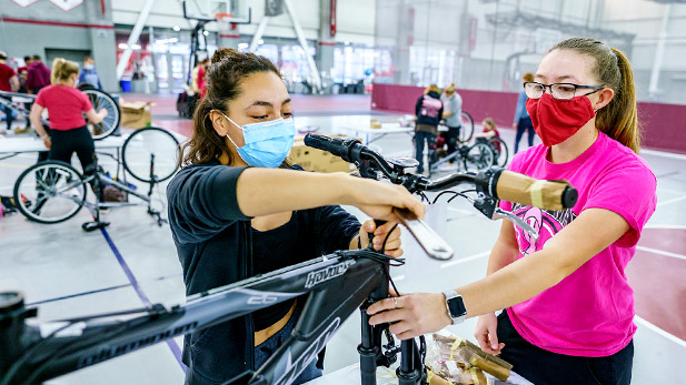 Two students assemble a bike in the Sports & Recreation Center.