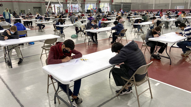 High school students solve math problems at tables in the Sports and Recreation Center.