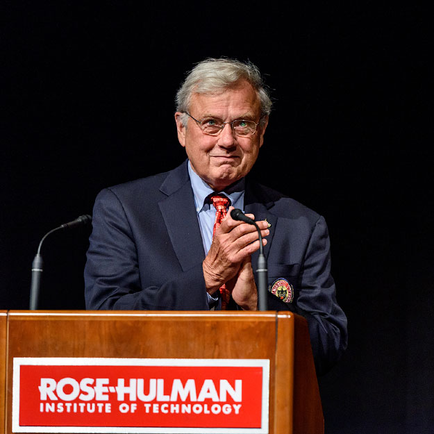 Niles Noblitt applauds from a podium at Rose-Hulman.