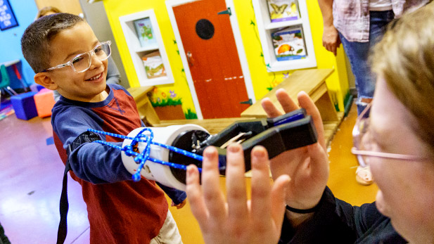 A Rose-Hulman student tests a prosthetic arm with a smiling child at the Terre Haute Children's Museum.
