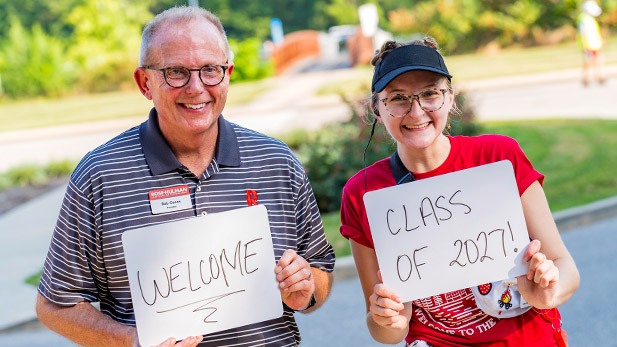 President Rob Coons and SGA President Courtney Valmore hold up signs welcoming students to campus.