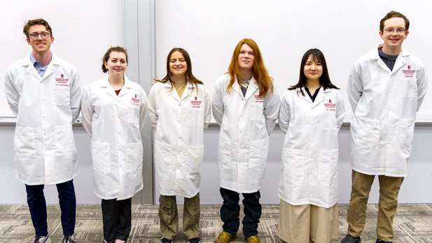 Six students proudly wear their new personalized lab coats.