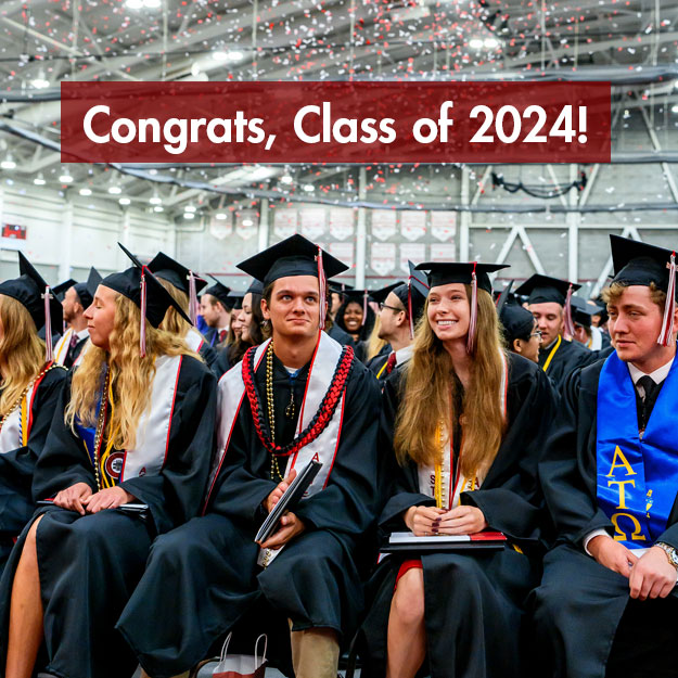 Graduates celebrate as red and white confetti falls.