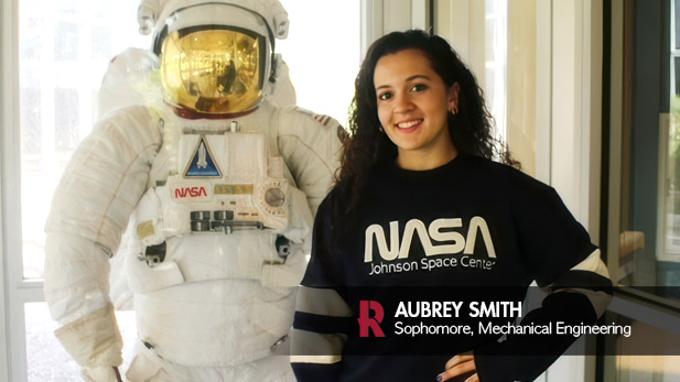 Aubrey Smith, a sophomore majoring in Mechanical Engineering, poses next to a NASA spacesuit display during her visit to the Johnson Space Center, where she is gaining hands-on experience through an internship.