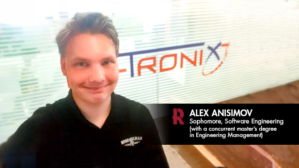 Alex Anisimov, wearing a Rose-Hulman polo, takes a selfie by a wall with the Wi-Tronix logo.