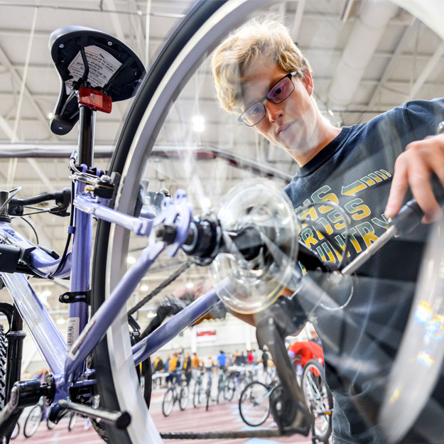 Three students inspect the tire of an assembled bike.