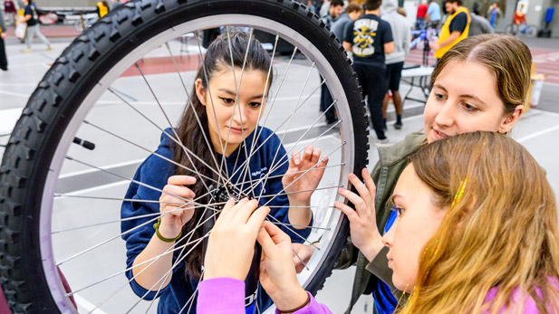 Three students inspect the tire of an assembled bike.