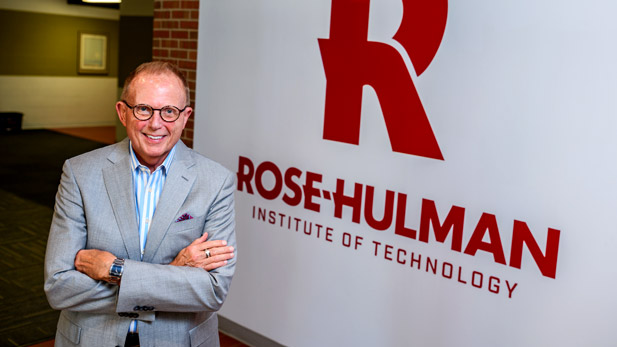 Rose-Hulman President Robert A. Coons poses in front of Rose-Hulman logo wall.
