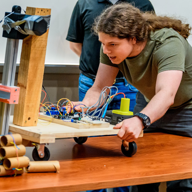 A team of students working on a project, with wires dangling in the foreground.