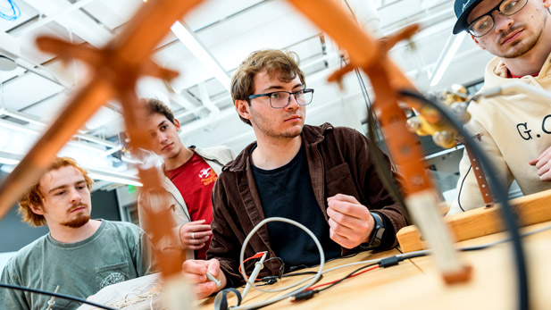 A team of students working on a project, with wires dangling in the foreground.