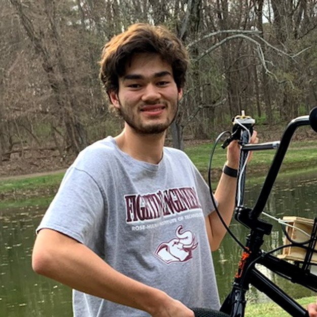 There are five photos. Left: Shaun Yamamoto holds the HCAC Cross Country Championship trophy. Second from left: Yamamoto holds the front of his electric bike. Middle: Yamamoto takes a hike during his study abroad in Japan. Second from right: Yamamoto enjoys a campus snowfall. Right: Yamamoto hikes across rocky terrain.