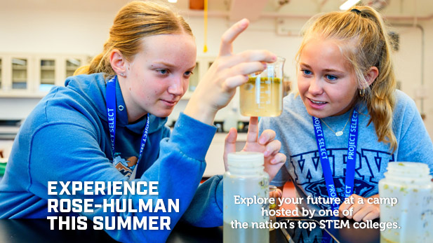 Two students wearing Project SELECT lanyards examine liquid in a beaker in a lab.