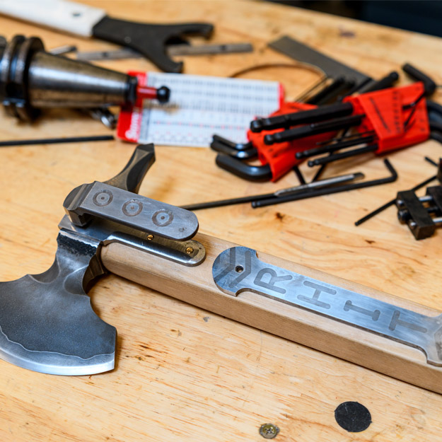 Cast in Steel team by a workbench with their axe.