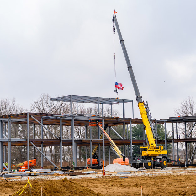 A crane lowers a beam to the highest point of the Innovation Grove structure.