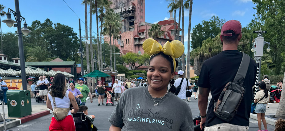 Jayden O'Dell in a Walt Disney Imagineering shirt and yellow mouse ears by the Tower of Terror in Disney's Hollywood Studios.