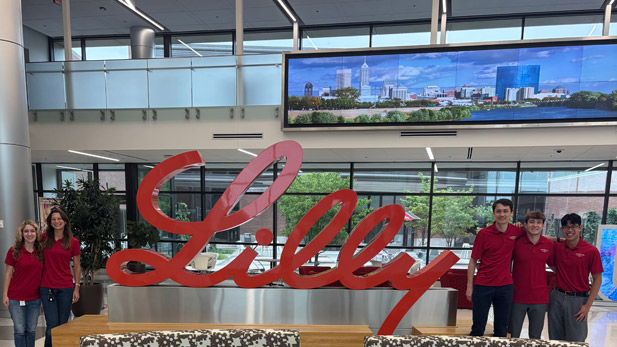 Five students in Rose-Hulman polos stand by a Lilly logo.