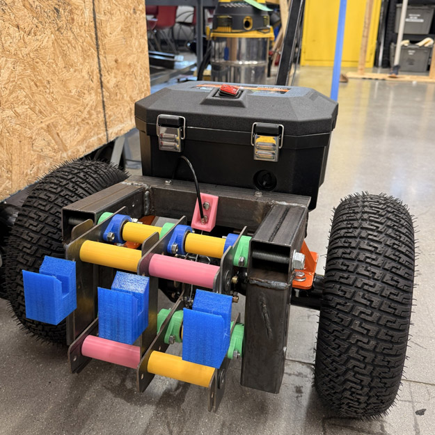 Students work on an electric book dolly with large wheels and 3D printed parts.