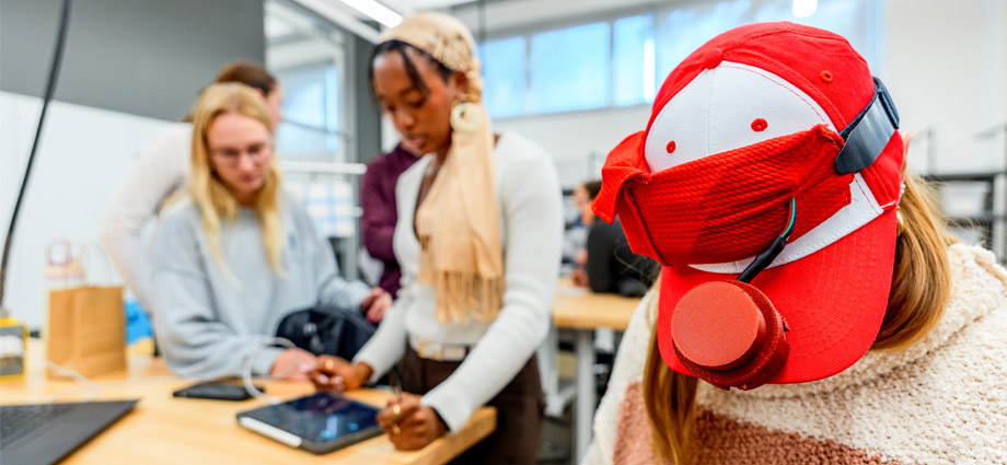 A student demonstrates her musical project with a baseball cap.